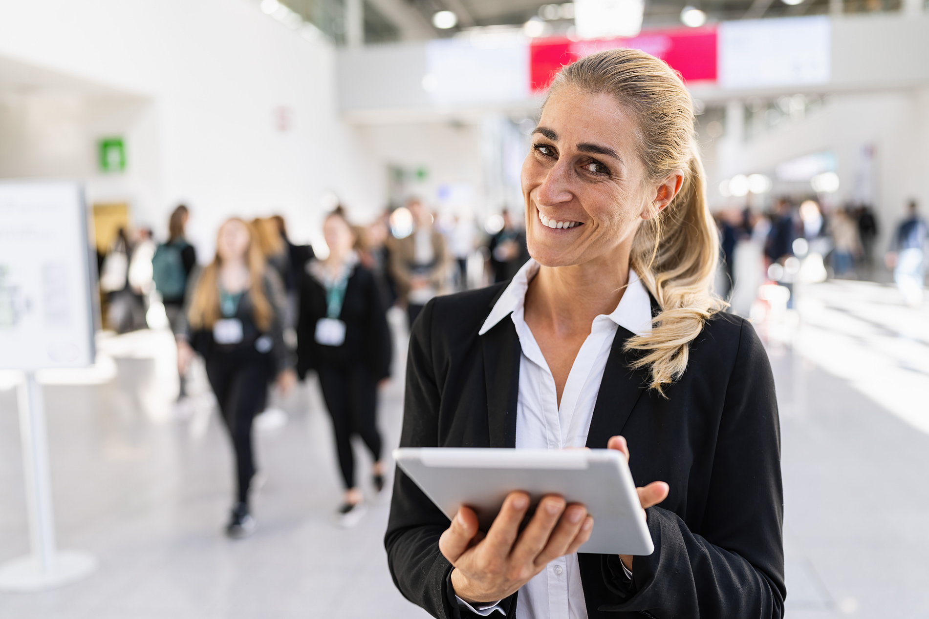 happy businesswoman at a trade fair holding tablet